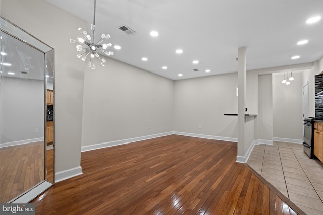 unfurnished living room with hardwood / wood-style floors and an inviting chandelier