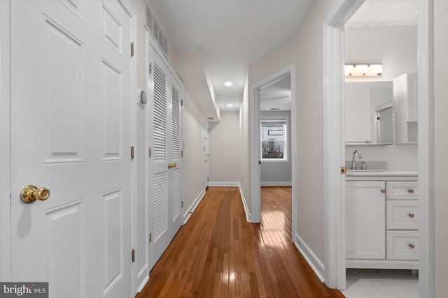 corridor featuring sink and light wood-type flooring