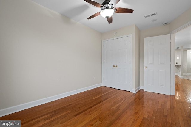 unfurnished bedroom featuring hardwood / wood-style floors, a closet, and ceiling fan