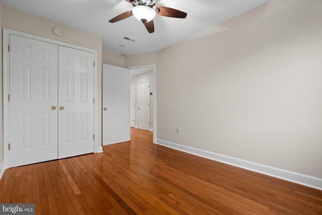 unfurnished bedroom featuring hardwood / wood-style flooring, ceiling fan, and a closet