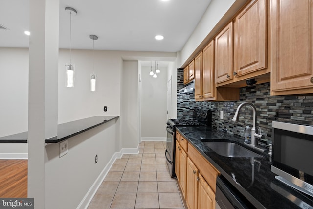 kitchen featuring tasteful backsplash, dark stone counters, stainless steel appliances, sink, and decorative light fixtures