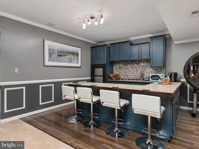 kitchen with crown molding, blue cabinetry, a breakfast bar, and backsplash