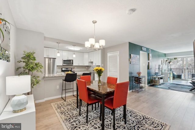 dining space featuring light hardwood / wood-style floors and a chandelier