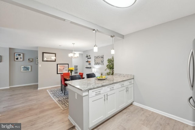 kitchen featuring kitchen peninsula, light stone counters, light hardwood / wood-style flooring, and white cabinets