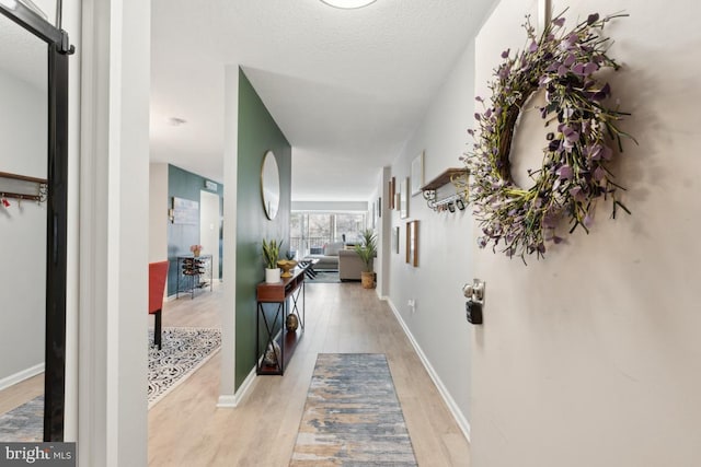 corridor featuring light wood-type flooring and a textured ceiling