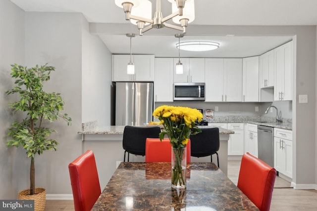 dining area featuring an inviting chandelier, sink, and light hardwood / wood-style flooring