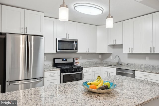 kitchen with appliances with stainless steel finishes, decorative light fixtures, and white cabinetry