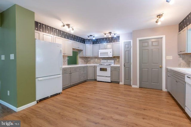 kitchen featuring white appliances, light hardwood / wood-style floors, tasteful backsplash, and gray cabinetry