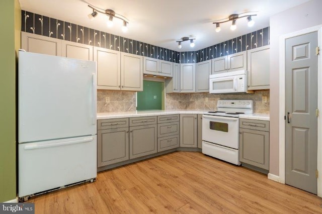 kitchen featuring light wood-type flooring, decorative backsplash, white appliances, and gray cabinetry