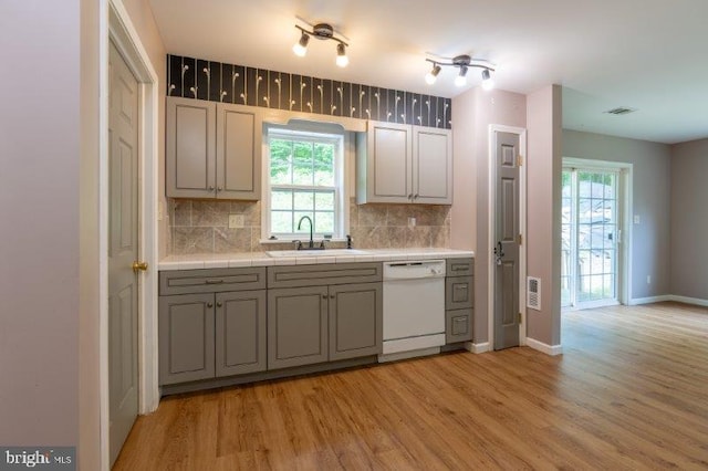 kitchen with white dishwasher, a wealth of natural light, light hardwood / wood-style floors, and sink