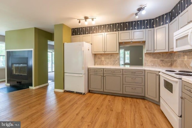 kitchen with decorative backsplash, white appliances, and light hardwood / wood-style floors