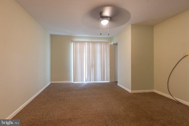 spare room with dark colored carpet and ceiling fan