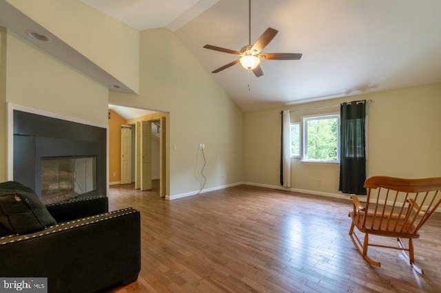 living area with ceiling fan, hardwood / wood-style floors, and high vaulted ceiling