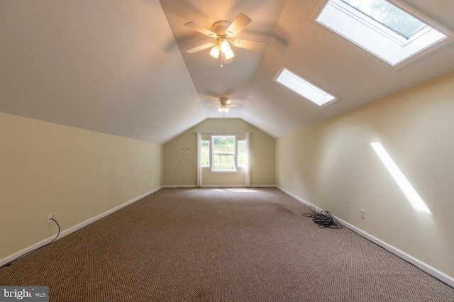 bonus room featuring vaulted ceiling with skylight, ceiling fan, and light colored carpet