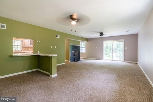 unfurnished living room featuring carpet, ceiling fan, a healthy amount of sunlight, and sink