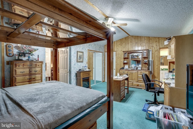 carpeted bedroom with a textured ceiling, ceiling fan, wood walls, and vaulted ceiling