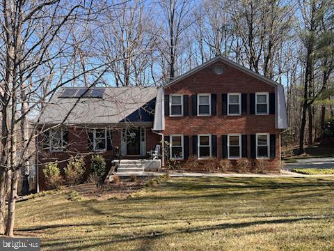 tri-level home with a front yard and solar panels