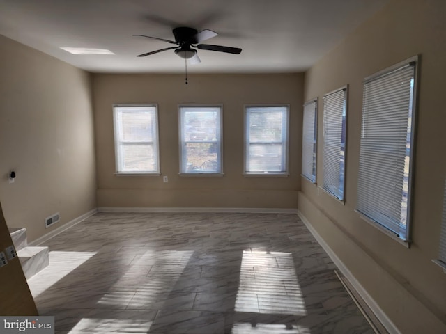 spare room with a ceiling fan, visible vents, and baseboards