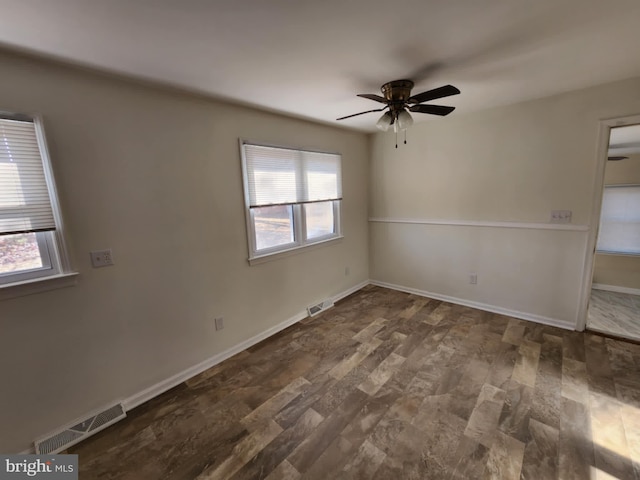 unfurnished room featuring dark wood-style flooring, visible vents, ceiling fan, and baseboards