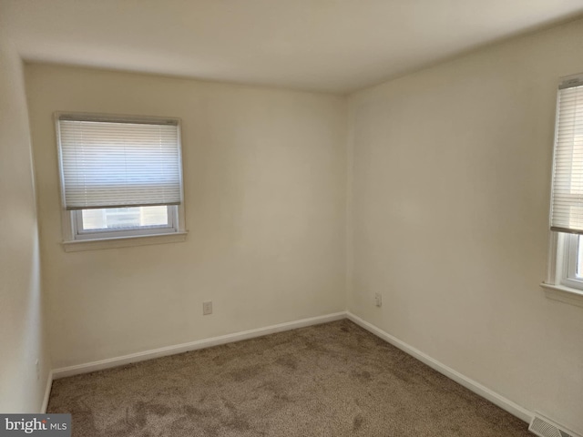 carpeted empty room with visible vents and baseboards