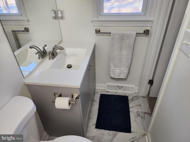 bathroom with toilet, vanity, visible vents, marble finish floor, and plenty of natural light