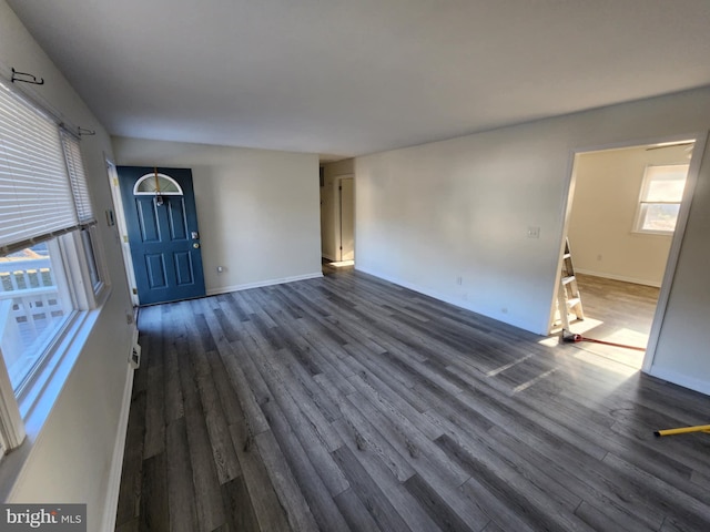 unfurnished living room featuring dark wood-style floors and baseboards