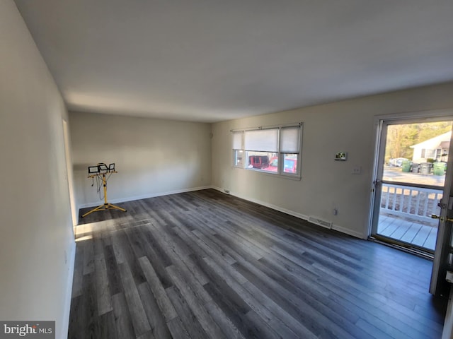 unfurnished living room with dark wood-style floors, visible vents, and baseboards