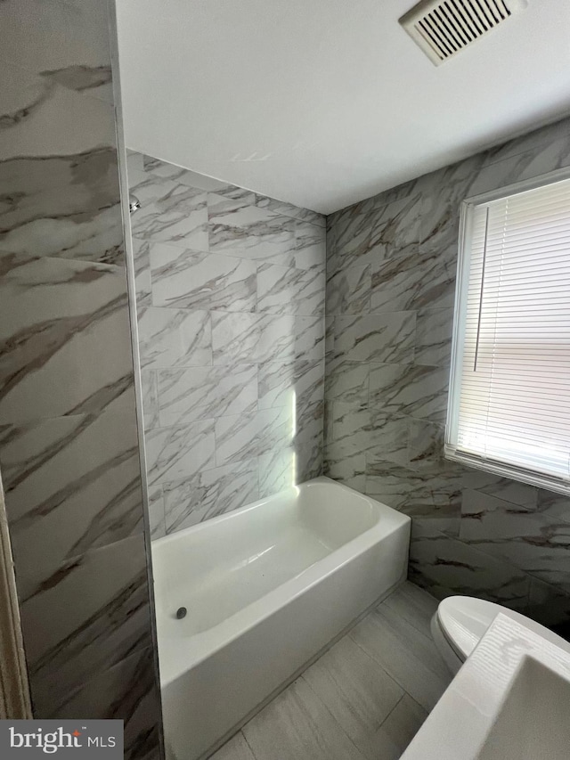 bathroom with toilet and tile walls