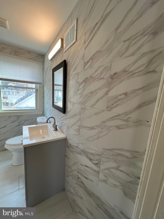 bathroom with vanity, tile walls, and toilet