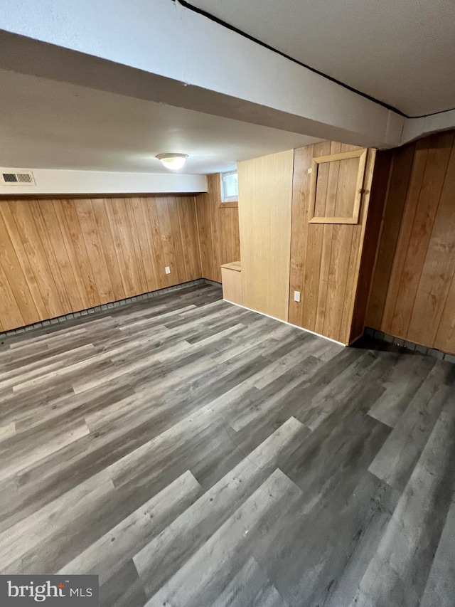 basement with dark wood-type flooring and wooden walls