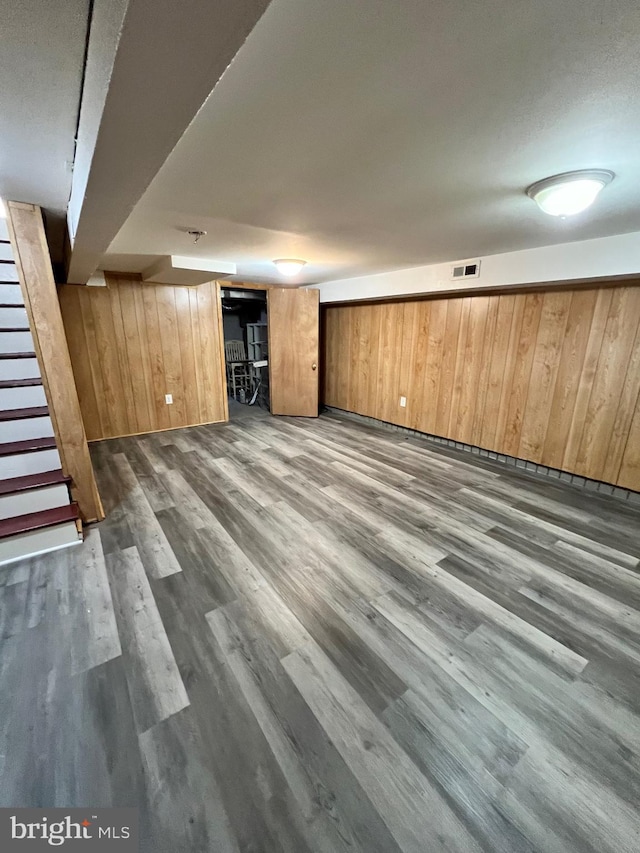 basement with wood walls and dark wood-type flooring