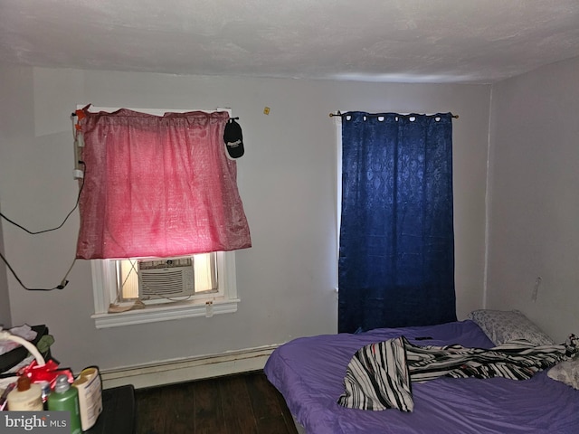 bedroom with cooling unit, dark wood-type flooring, and a baseboard radiator