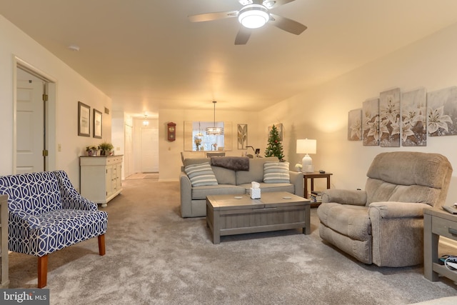 carpeted living room featuring ceiling fan with notable chandelier