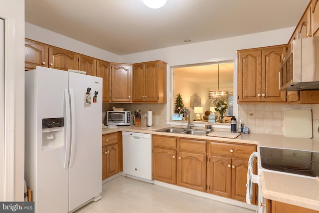 kitchen with white appliances, tasteful backsplash, hanging light fixtures, and sink