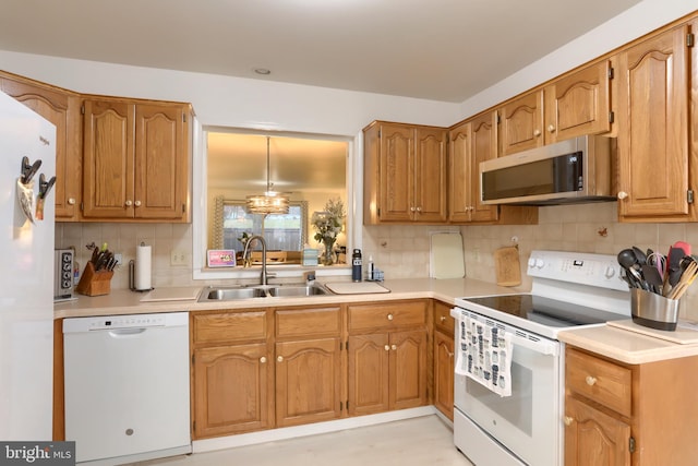 kitchen with pendant lighting, white appliances, sink, and tasteful backsplash