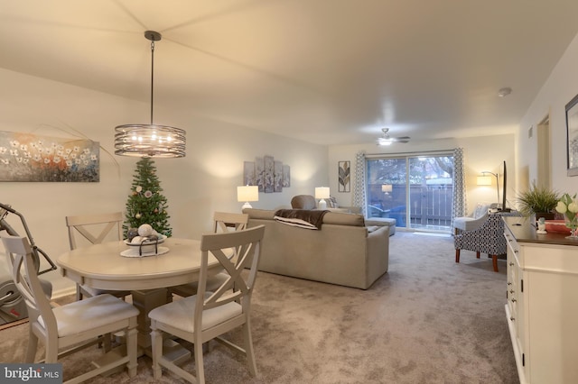 carpeted dining room with ceiling fan with notable chandelier