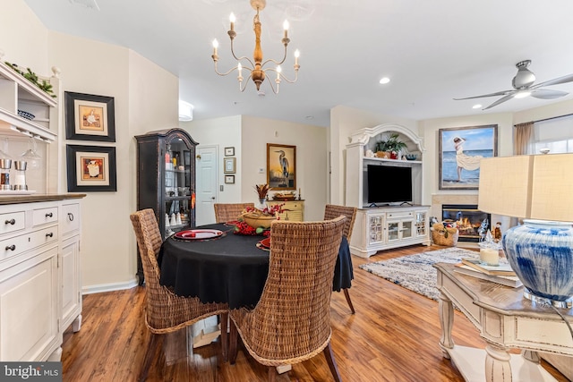 dining space with hardwood / wood-style floors and ceiling fan with notable chandelier