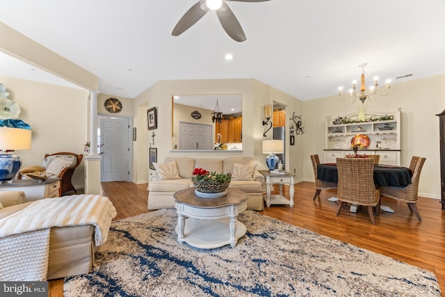 living room with ceiling fan with notable chandelier, decorative columns, and light hardwood / wood-style flooring