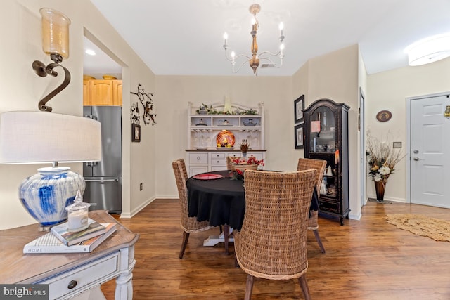 dining space with hardwood / wood-style floors and an inviting chandelier