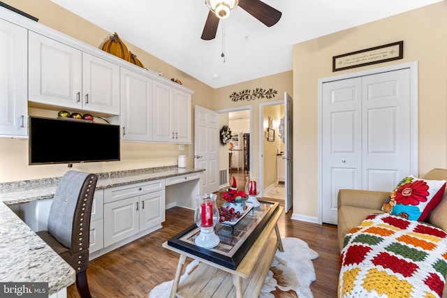 interior space featuring dark hardwood / wood-style flooring, built in desk, and ceiling fan