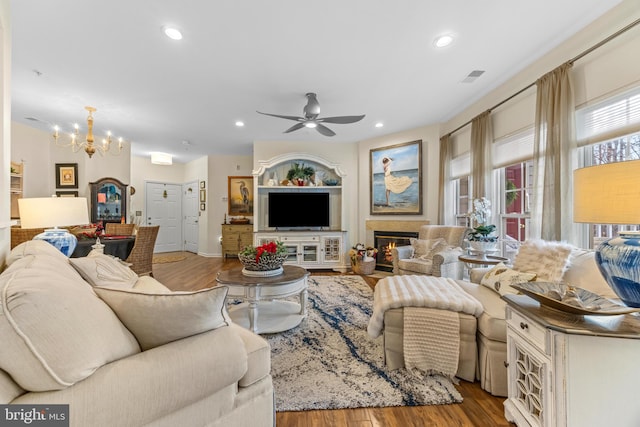 living room with ceiling fan with notable chandelier and light hardwood / wood-style floors