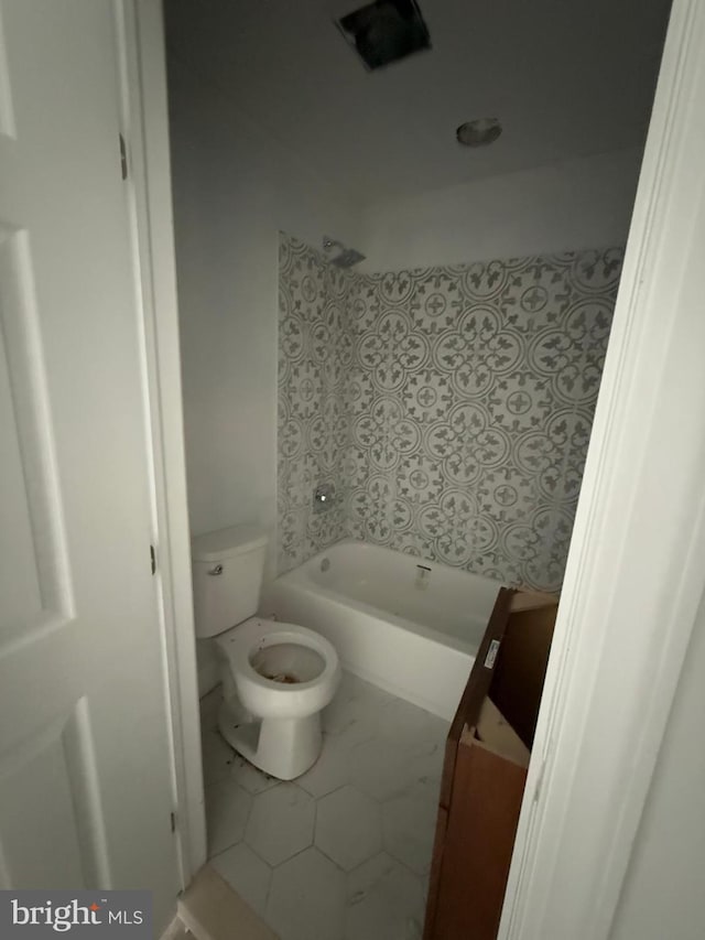 bathroom with tile patterned floors, a tub to relax in, and toilet