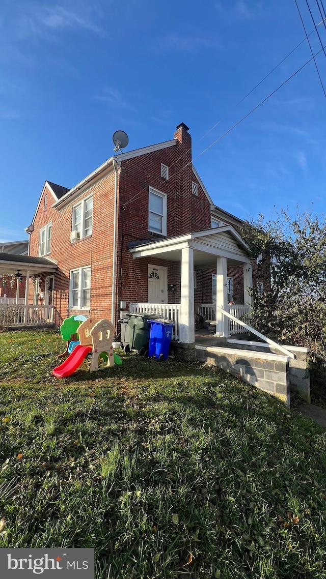 rear view of house featuring a lawn and a porch