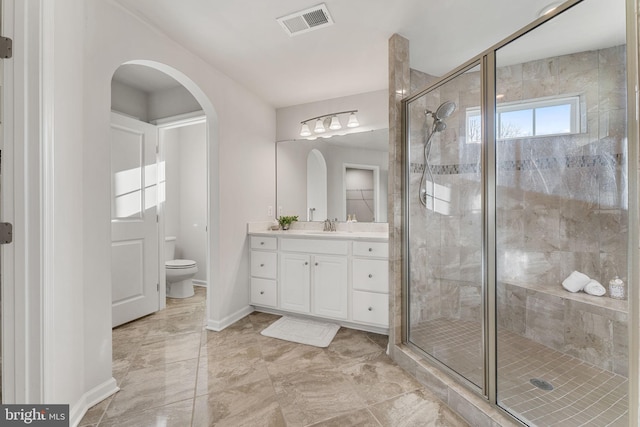 bathroom with a shower with door, vanity, and toilet