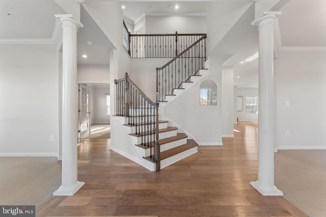 staircase with ornate columns and crown molding