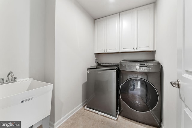 clothes washing area featuring cabinets, sink, and washing machine and clothes dryer