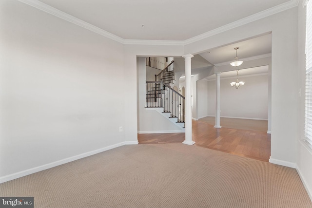 carpeted spare room with ornate columns, crown molding, and a notable chandelier