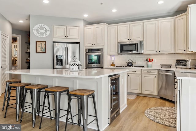 kitchen featuring light wood-type flooring, stainless steel appliances, wine cooler, and a kitchen island