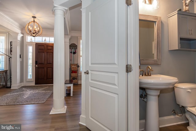 foyer featuring a notable chandelier, dark hardwood / wood-style flooring, crown molding, and decorative columns