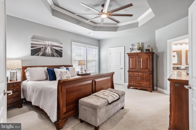 carpeted bedroom featuring a tray ceiling, ensuite bath, ceiling fan, and ornamental molding